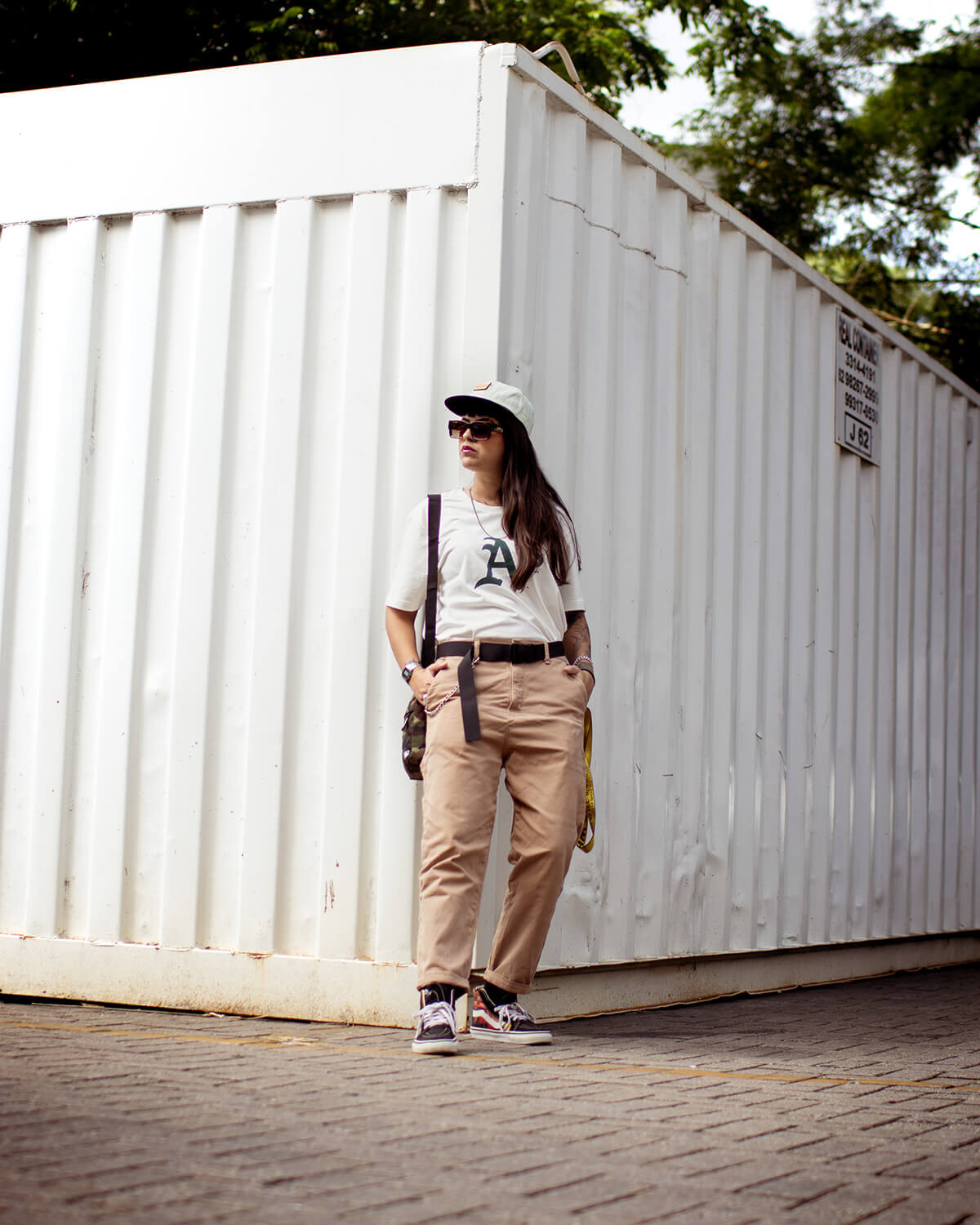 Moda streetwear - Modelo com camiseta A, calça bege e boné em container branco